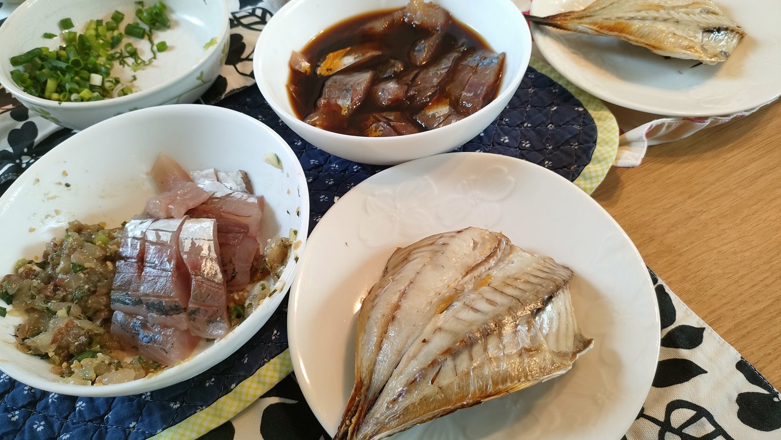 釣ったアジで作った料理が並ぶ食卓。刺身となめろう、しょうゆ漬け、開きの焼き物、薬味のねぎ。